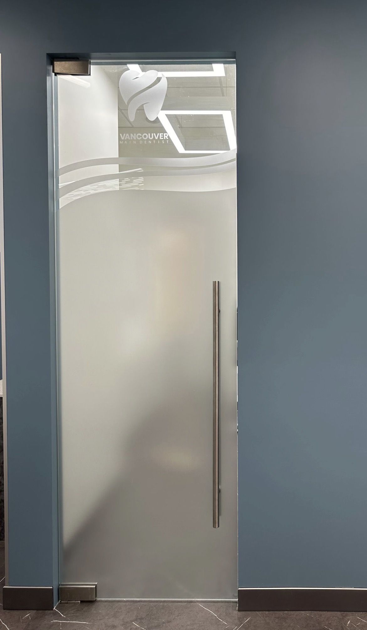 Frosted vinyl privacy film with a custom logo cut-out on a glass sliding door in a Vancouver clinic